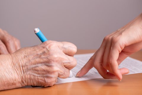 anciana firmando un documento